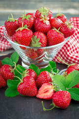 Ripe, fresh strawberries in a bowl on an old background.