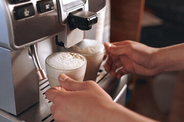 the Barista prepares two cappuccinos with a coffee machine for lunch