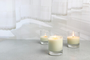 Fototapeta na wymiar The luxury lighting aromatic scent glass candle diplay on the grey table in the white bedroom with background of the curtain