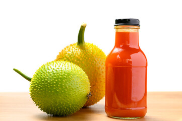 Spiny bitter gourd juice in bottle with fruits on white background
