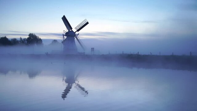 Windmill 'de Witte Molen' reflected in the canal during a foggy dawn in Holland.
