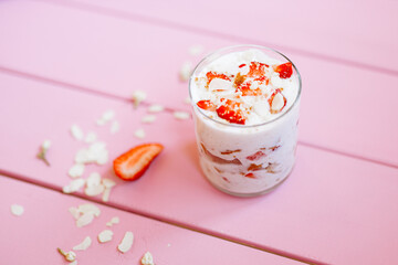 layered summer dessert with strawberries, sponge cake and yogurt on a pink tree background.