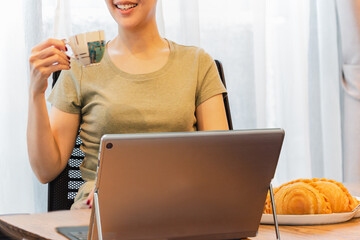 Businesswoman smiling with hand holding and snack with open laptop on table.