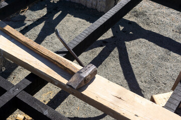 Old sledgehammer on board at a construction site of wooden house