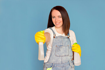 Happy woman cleaning lady with a bucket full of colorful detergents in rubber gloves holding cleaning chemicals in her hands