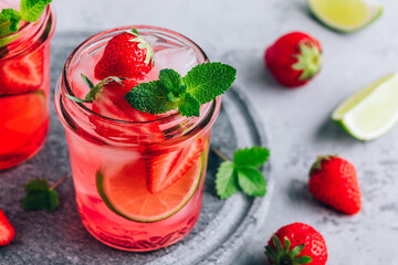 Strawberry lime lemonade with fresh mint and ice in glass jar.