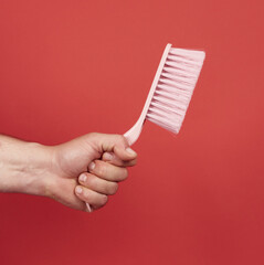 male hand holds pink plastic cleaning brush