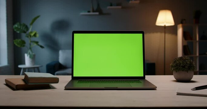 Close up shot of modern chroma key green screen laptop computer set up for work on desk at night - remote work, technology concept 4k video template