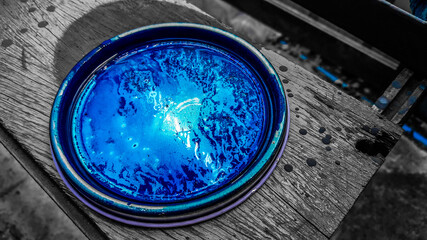 Round tray with blue acrylic paint placed on a wooden floor