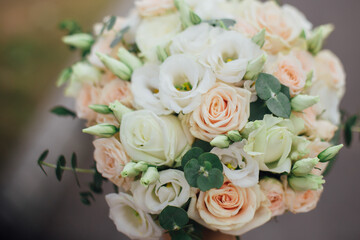 Wedding bouquet in the hands of the bride of white roses and other flowers