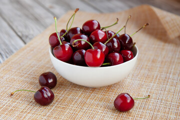 cherry berries in a white Cup, light kitchen napkin, light wooden background