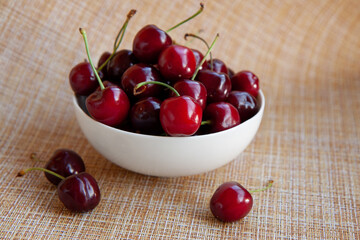 cherry berries in a white Cup, light kitchen napkin, light wooden background
