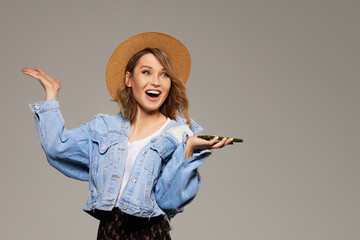 Joyful young girl in a hat with a mobile phone in her hands. The concept of 5G cellular and unlimited internet for entertainment.