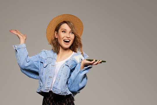 Joyful young girl in a hat with a mobile phone in her hands. The concept of 5G cellular and unlimited internet for entertainment.
