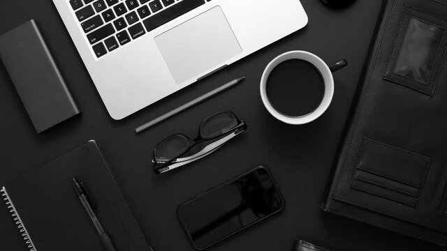 Business desktop concept. Mix of office supplies and gadgets on a black table background