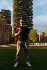 Frontal portrait of stylish man in sporty clothes on sunset city background pose to camera Young man on urban street