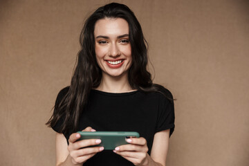 Fototapeta premium Photo of young woman smiling and playing video games on cellphone