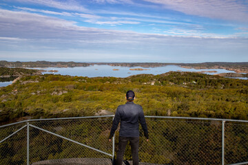 Fototapeta na wymiar Person his back to the camera watching a scenic view of swedish coastal landscape from an elevated vantage point