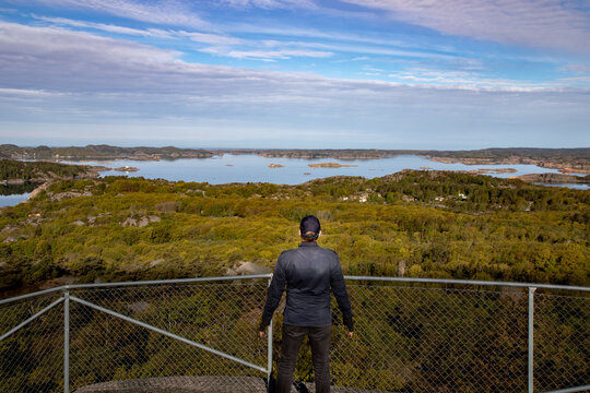 Person his back to the camera watching a scenic view of swedish coastal landscape from an elevated vantage point
