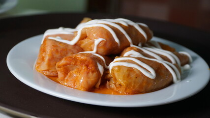 Stuffed cabbage under sour cream. A dish of Ukrainian cuisine cabbage rolls with sour cream on a white plate.