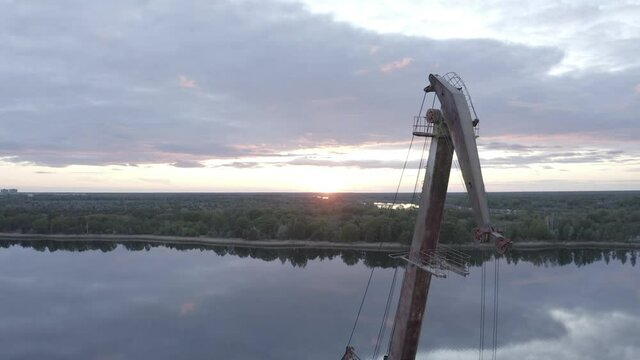 Cranes that took part in the liquidation of the accident at the Chernobyl nuclear power plant on which birds sit with a view of the sarcophagus aerial photography. On the Sunset