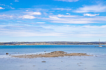 Small reef surrounded by blue ocean and distant coastline