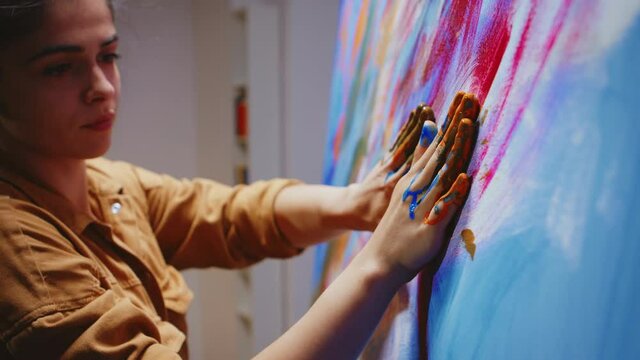 Close up of painting with fingers on large canvas in art studio. Modern artwork paint on canvas, creative, contemporary and successful fine art artist drawing masterpiece