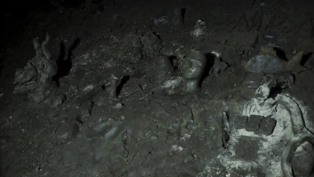 Closeup view of crumbled statues which are located in a dark cave.