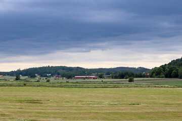 Rural view of fields and a barn with heavy rain clouds in the sky