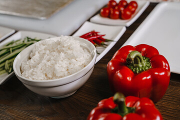 Boiled rice in a bowl surrounded by vegetables .Food preparation