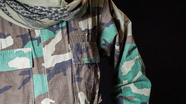 Close up of male soldier's BDU shirt and green shemagh scarf. Military camo uniform