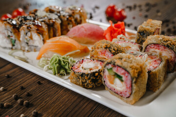 Rolls and sushi on a plate surrounded by vegetables and spices. The serving of the meal