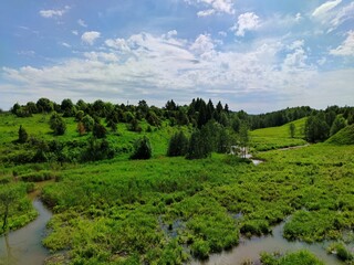 green hilly marshland against a beautiful blue sky with clouds