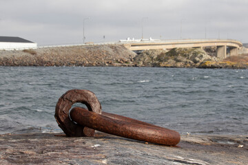 A rusty iron mooring by the sea. It is drilled into the rock