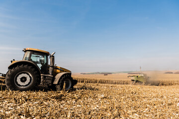 Obraz premium tractors harvesting golden field against blue sky