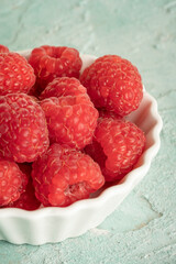 closeup red ripe raspberry fruits in a white bowl