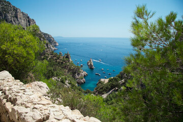 Fototapeta na wymiar panoramic view of the turquoise sea with some boats from the mountains full of rocks and green bushes under the blue sky at the Calanque de Sugiton in Marseille in France