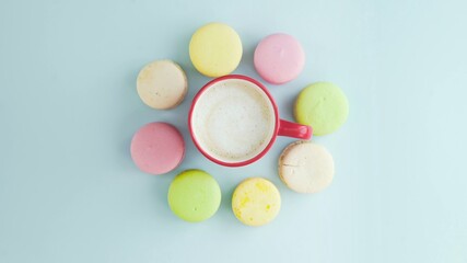 Macaroons or macaron on pastel blue surface with espresso in white cup.