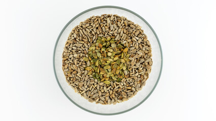 peeled sunflower seeds and pumpkin seeds in a plate on a white background, isolates