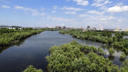 Fototapeta na wymiar A wide river flows among green banks. Summer landscape