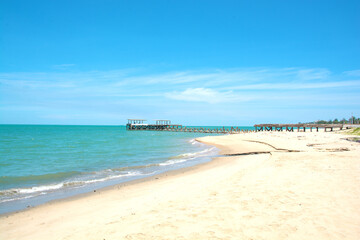 Fototapeta na wymiar Old pier or a bridge is broken on the beach into the sea with blue sky at Hua Hin District, Thailand