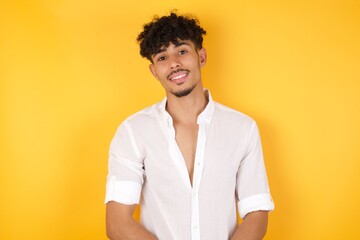 Gorgeous smiling male with broad smile, shows white teeth, wears casual t shirt, stands over gray studio wall rejoices having day off. Man standing indoors.