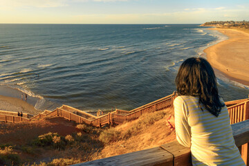 Fototapeta na wymiar Woman standing on iconic Port Noarlunga boardwalk while watching beautiful sunset, South Australia