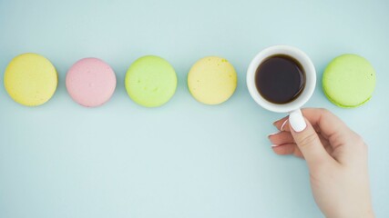 Obraz na płótnie Canvas Macaroons or macaron on pastel blue surface with espresso in white cup.