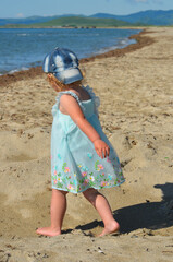 Happy and carefree childhood. A little girl in a turquoise dress walks on a sandy beach in the summer lifestyle