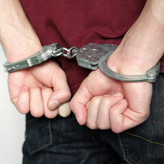 The criminal was detained by the police. The handcuffed hands clenched into fists.