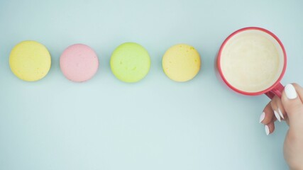 Macaroons or macaron on pastel blue surface with espresso in white cup.