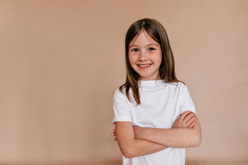 Obraz premium Studio shot of little charming lady wearing white t-shirt posing at camera over isolated background with great smile.
