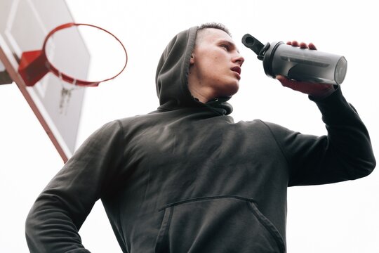 The Athlete Drinks A Drink From Shaker During A Workout. Fitness Trainer Man Drinks Sports Supplements Before Exercise