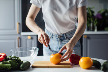 Close-up of the hands of a girl who cuts vegetables for salad. Healthy food